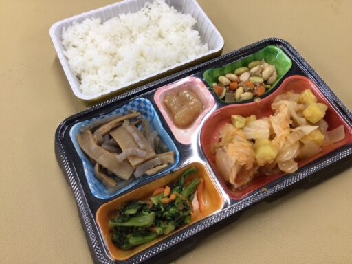 介護施設の栄養バランスの取れた食事トレー。ご飯、野菜、たんぱく質が配分された弁当。